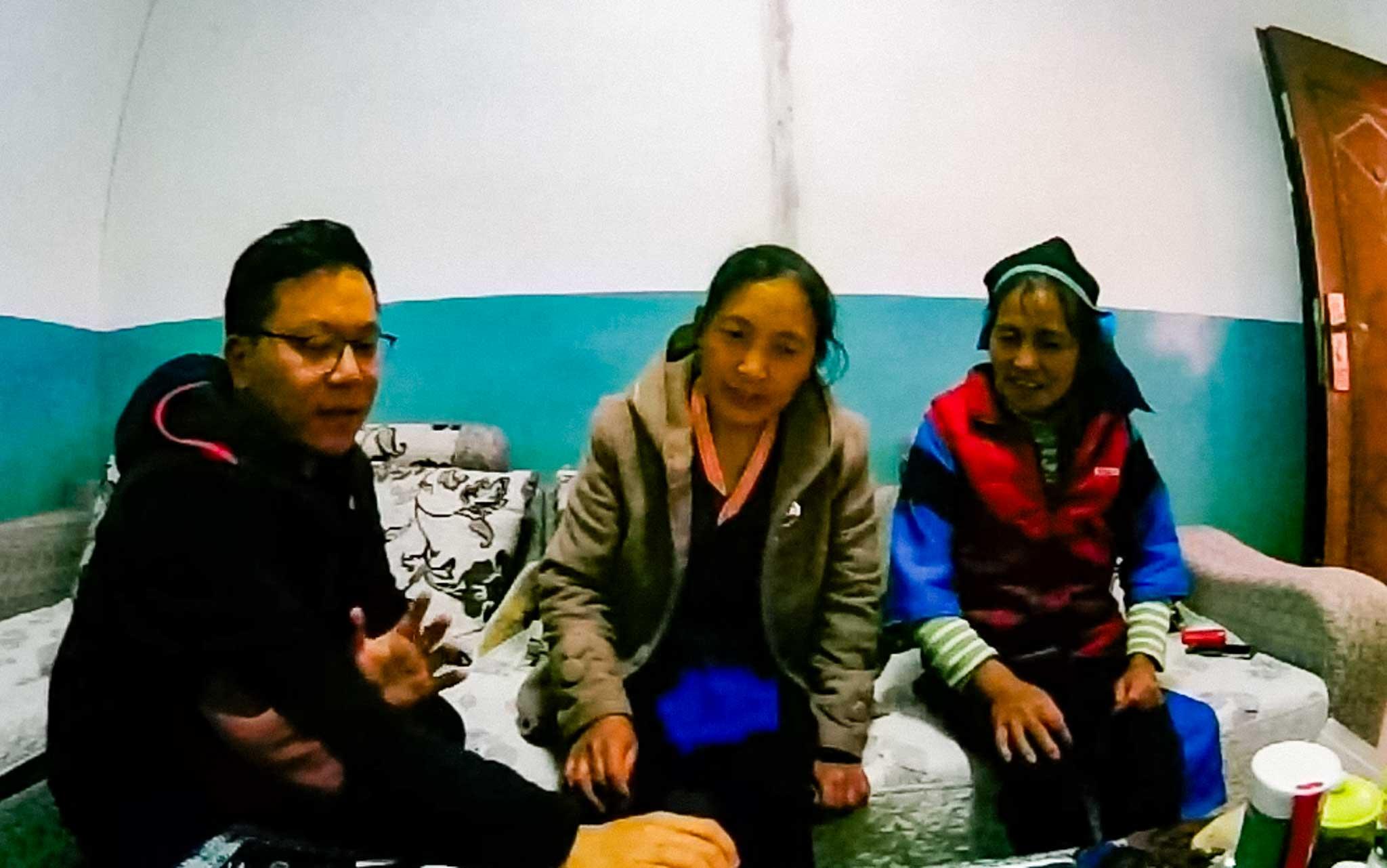 Huade sits with Wuxing villagers conducting his research.
