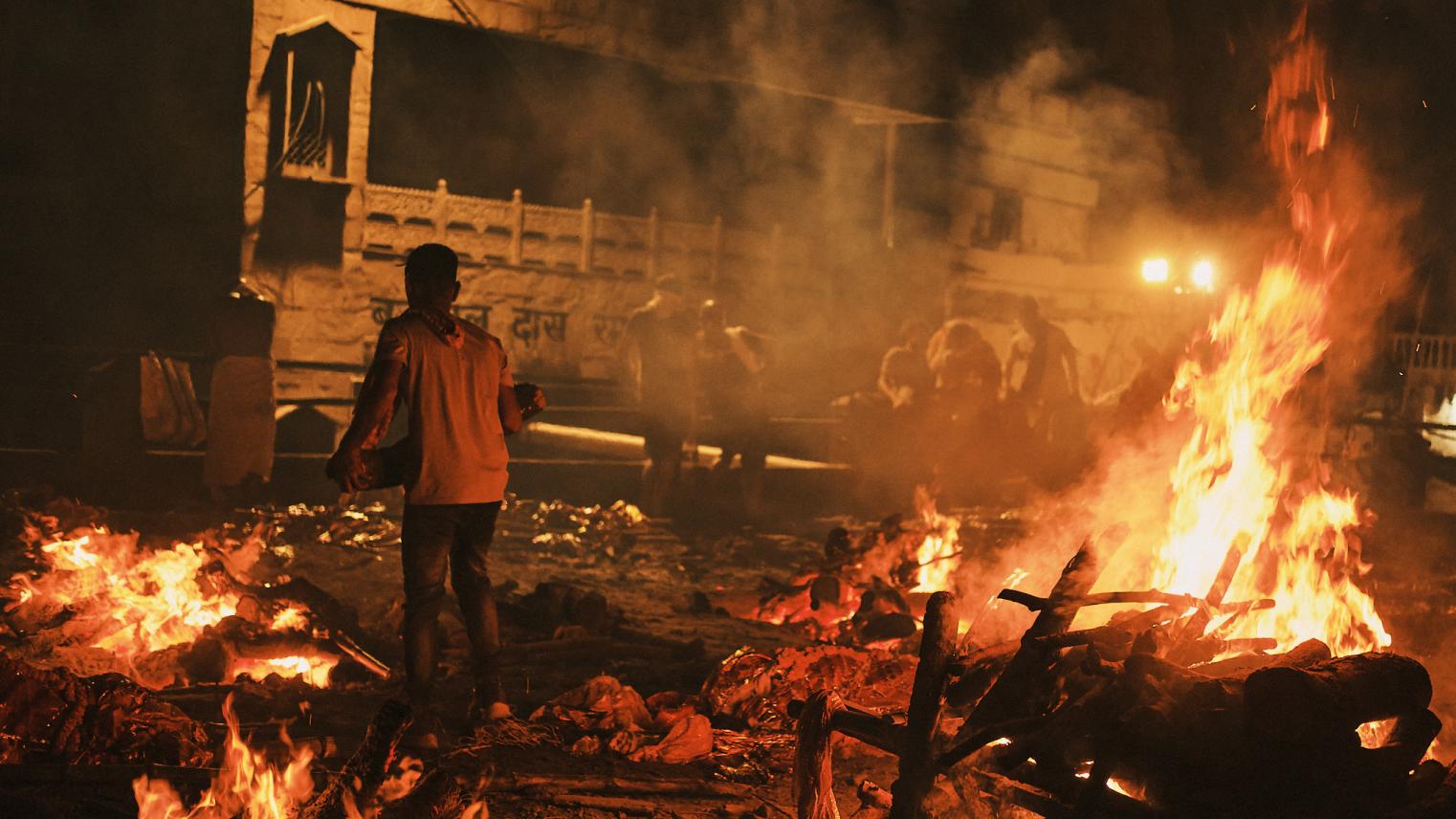 A dom moves donated wood between cremation pyres on a ghat rooftop in Varanasi, India.
