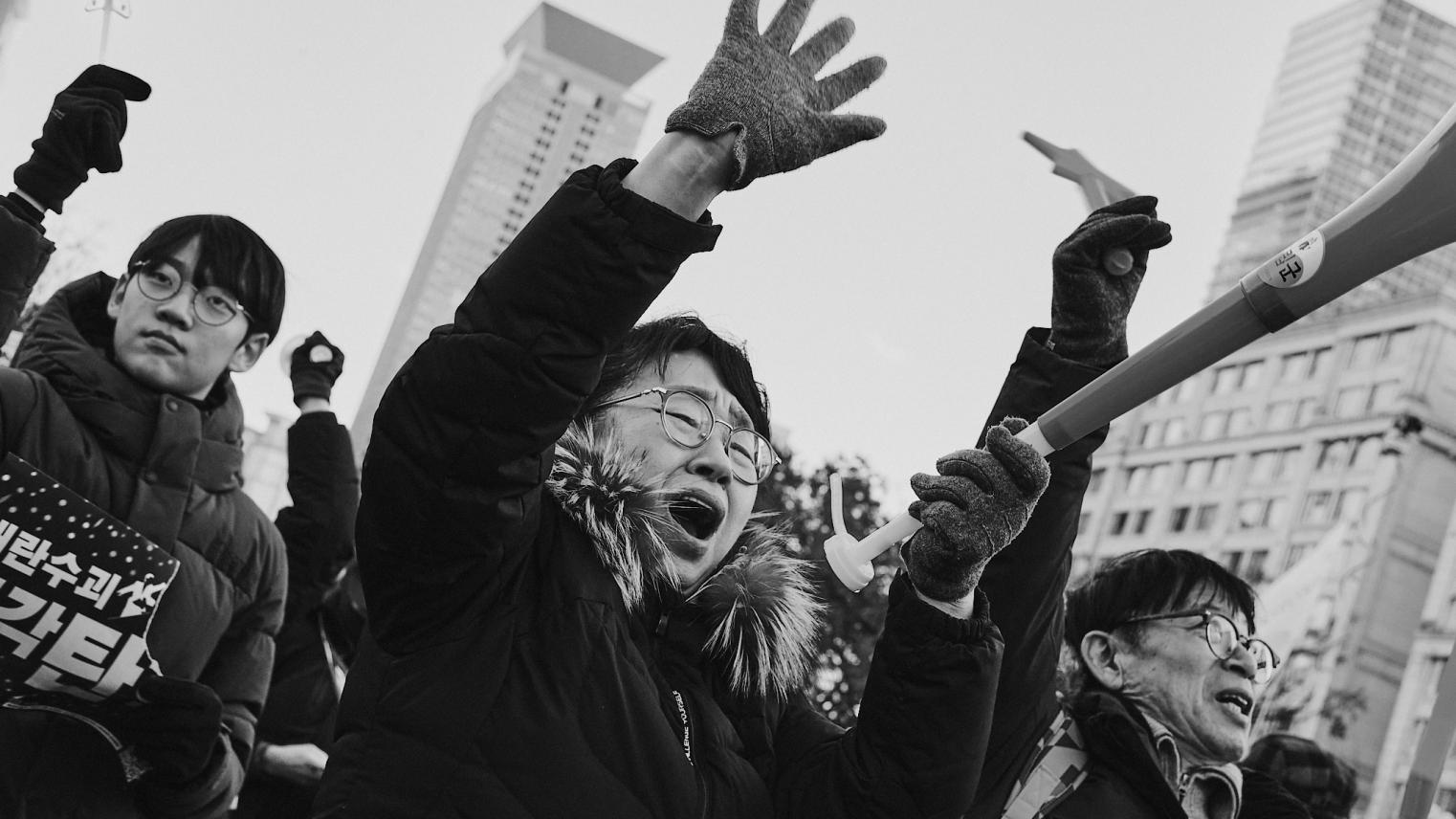 Protesters cheer outside the National Assembly of South Korea as the impeachment vote against former President Yoon is declared successful.